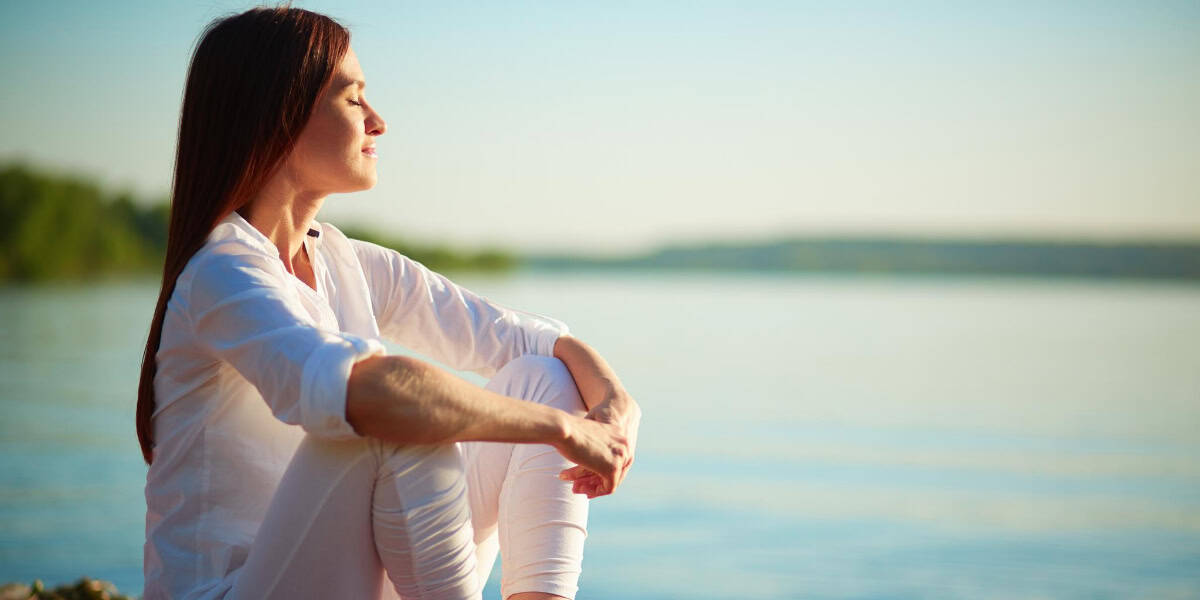 Woman seated by water enjoying the moment