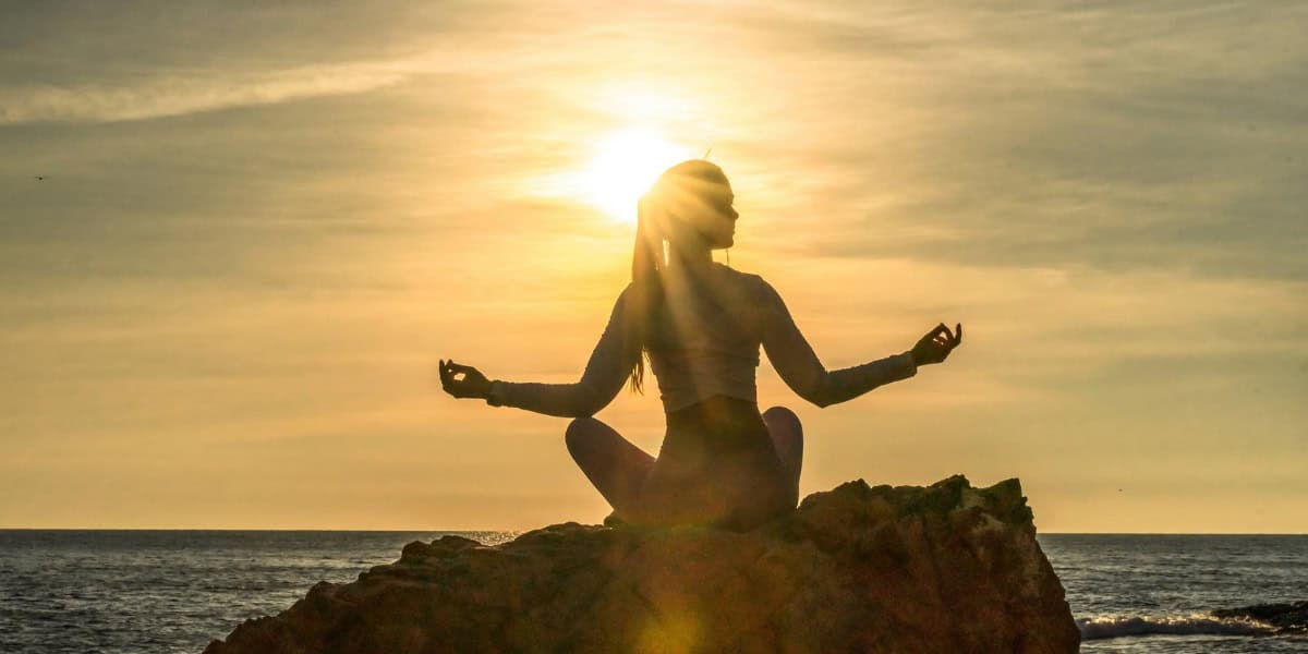 You woman meditating at sunset