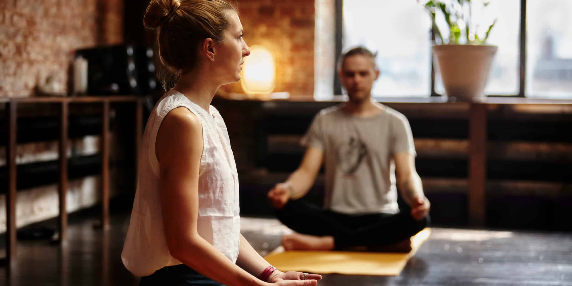 Two people meditating in a yoga studio.