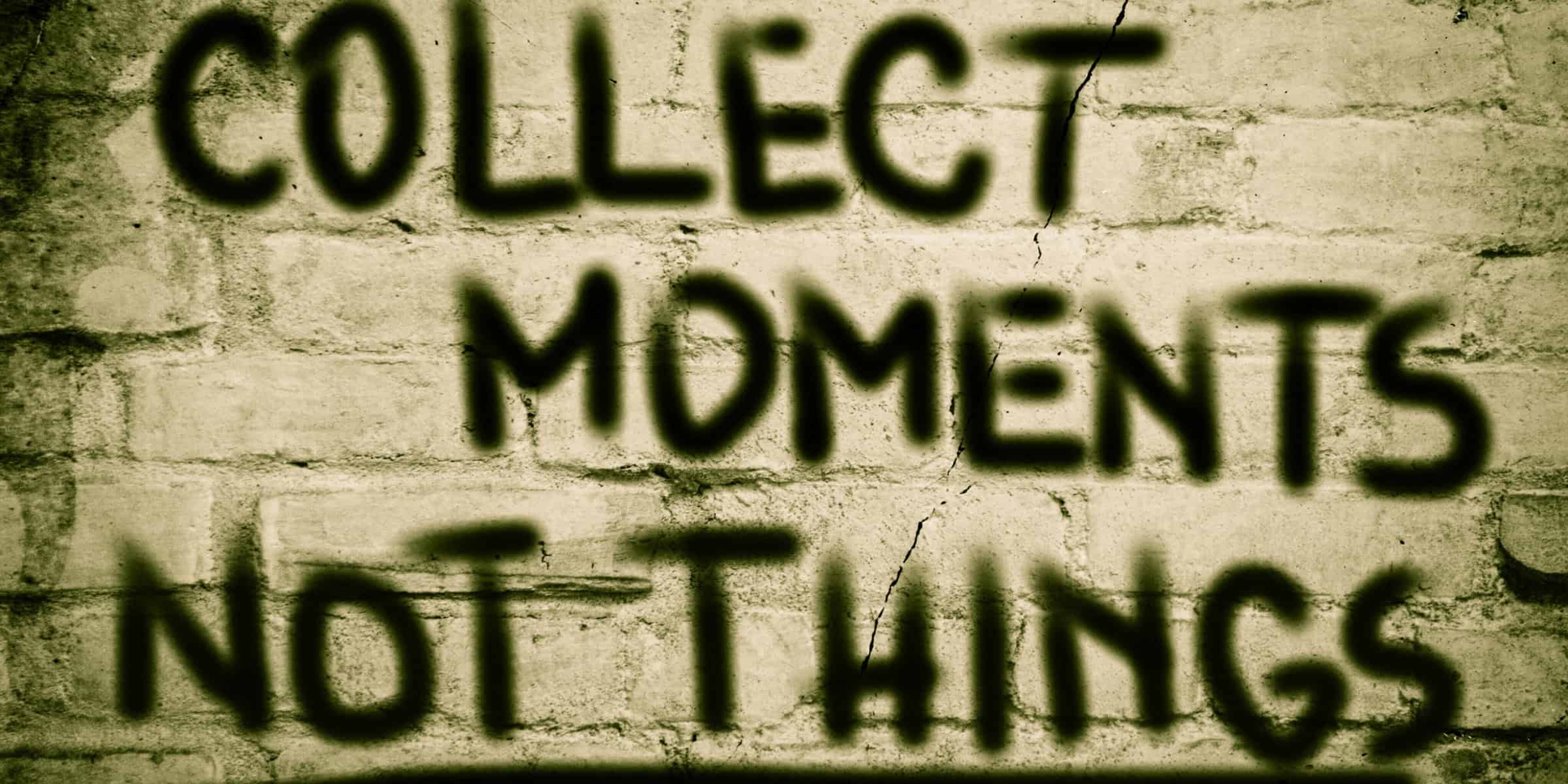 A brick wall with the words collect moments not things written on it.