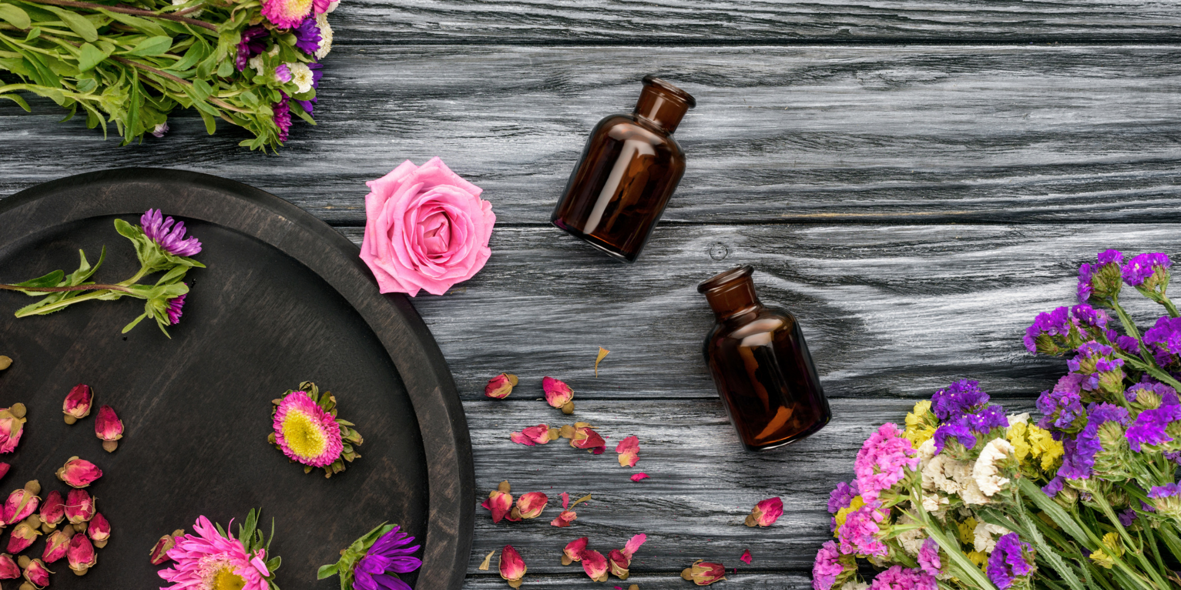Essential oils and flowers on a wooden table.