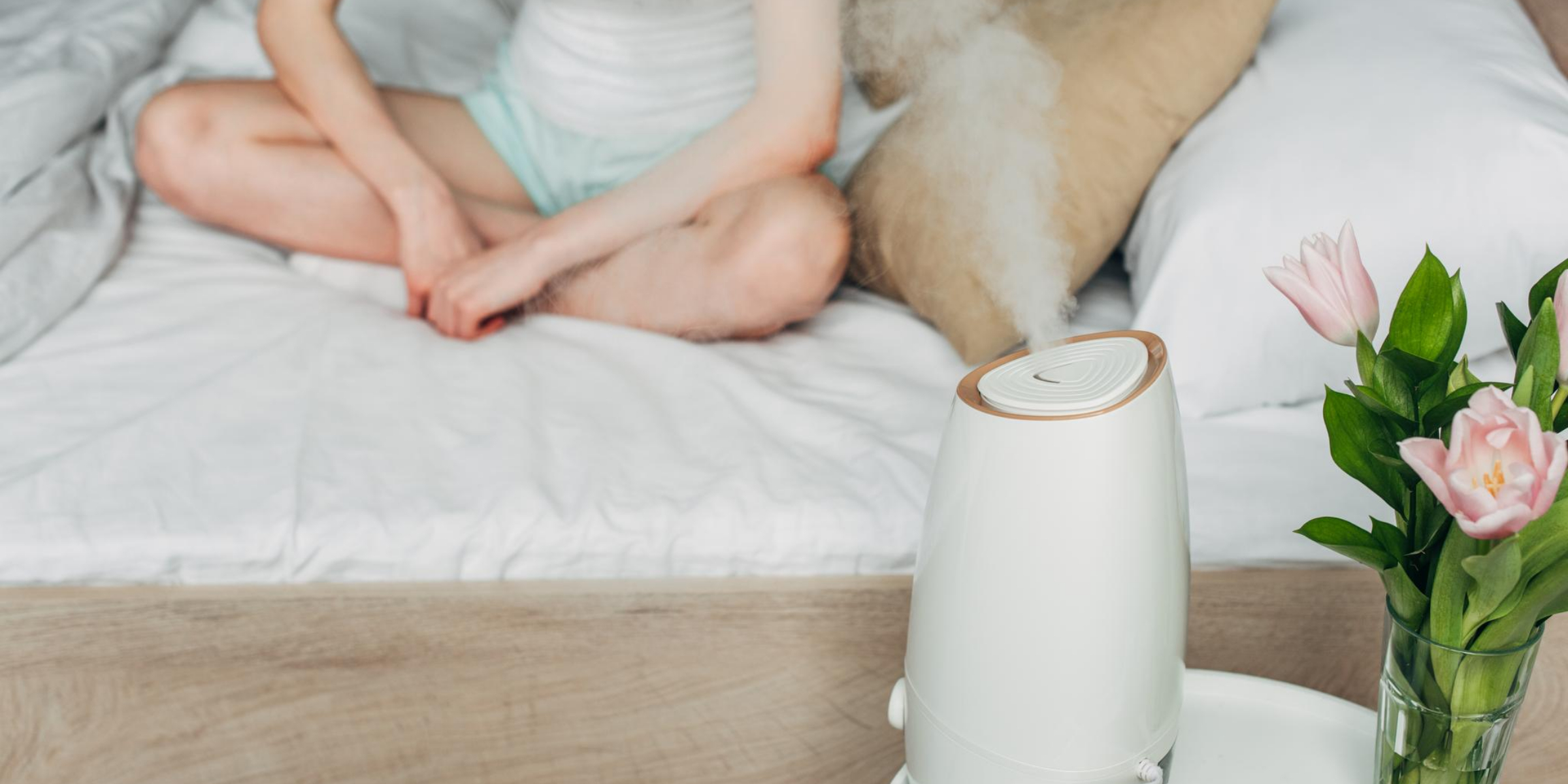 A woman is sitting on a bed with a Diffuser.