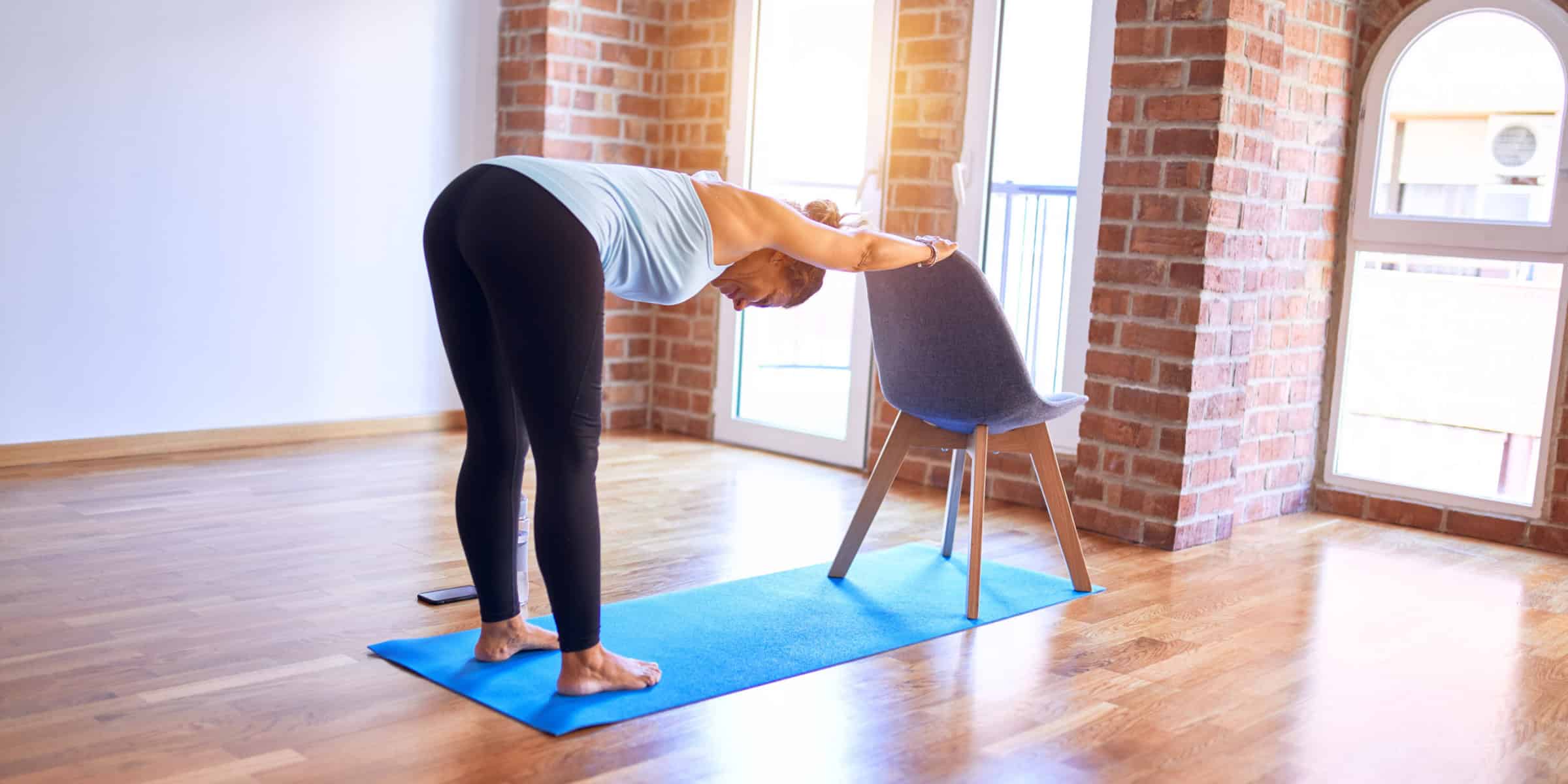 A woman doing a yoga pose in front of a window.