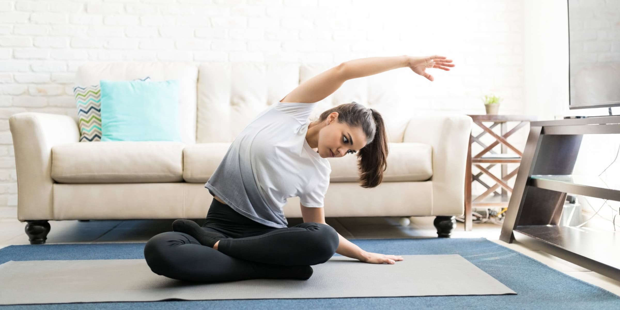 A woman doing yoga in front of a tv.