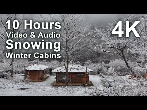 Two small wooden cabins are surrounded by trees and covered in snow, with text indicating a 10 hour 4K video of snowing at winter cabins.
