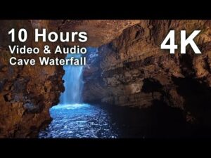 View of a waterfall inside a cave with blue water, rocky walls, and text overlay stating "10 Hours Video & Audio Cave Waterfall 4K".